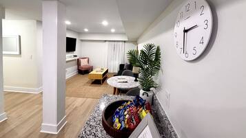 Una sala de estar moderna con una mesa de centro redonda, un sofá cómodo, un televisor montado en la pared y un reloj de pared grande.