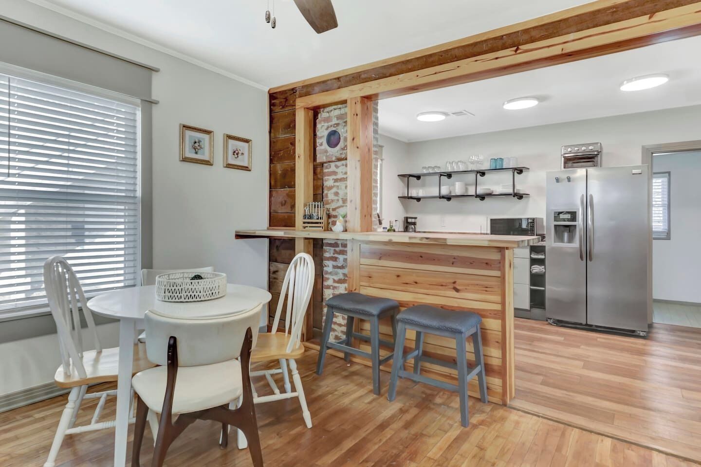 Une cuisine moderne agrémentée d’éléments en bois, un coin repas avec des chaises blanches et un bar intégré.