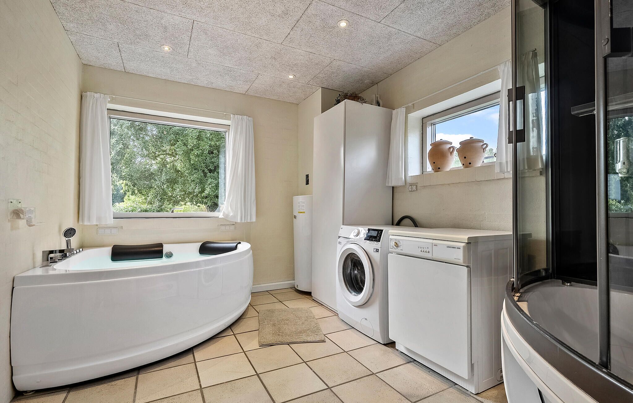Bagno compatto con vasca, lavatrice e frigorifero.