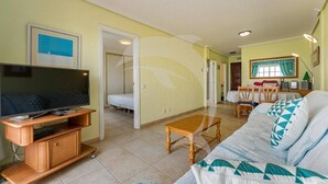 A living room with a TV, sofa, and dining area. - Beatifull Apartam 14A 2 Bedroom Sea Medano (Granadilla de Abona)