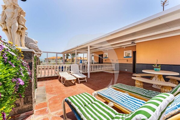 A rooftop terrace with lounge chairs, a statue, and a view of the city. - Beatifull Apartam 14A 2 Bedroom Sea Medano (Granadilla de Abona)