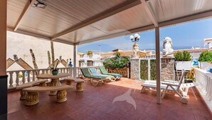 A covered outdoor patio with stone tables, lounge chairs, and decorative statues. - Beatifull Apartam 14A 2 Bedroom Sea Medano (Granadilla de Abona)