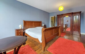 A bedroom with a wooden bed, a nightstand, a table, and a wardrobe. - 3 bedroom nice home in Saint-Simon (Saint-Simon)