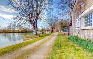 A narrow path beside a river, flanked by leafless trees and a building with a window. - 3 bedroom nice home in Saint-Simon (Saint-Simon)