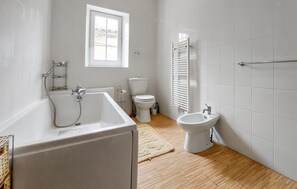 A modern bathroom with a bathtub, toilet, bidet, and a window providing natural light. - 3 bedroom nice home in Saint-Simon (Saint-Simon)