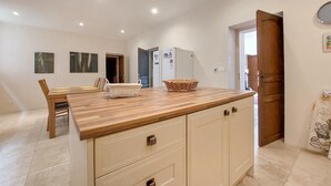 Une cuisine dotée d’un plan de travail en bois, de meubles blancs et d’un coin repas avec une table et des chaises.