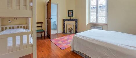 A bedroom with a bunk bed, a single bed, a fireplace, and a window.