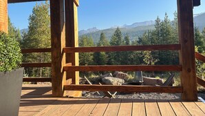 A wooden deck with a view of a forest and mountains.