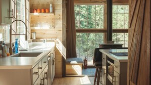 A modern kitchen with wooden beams, large windows, and a view of the outdoors.