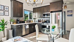 Una cocina moderna con armarios de madera oscura, electrodomésticos de acero inoxidable y una mesa de comedor de vidrio.