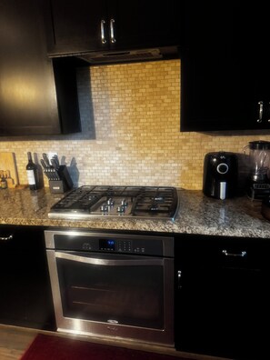 A kitchen with a gas stove, oven, and a coffee maker.