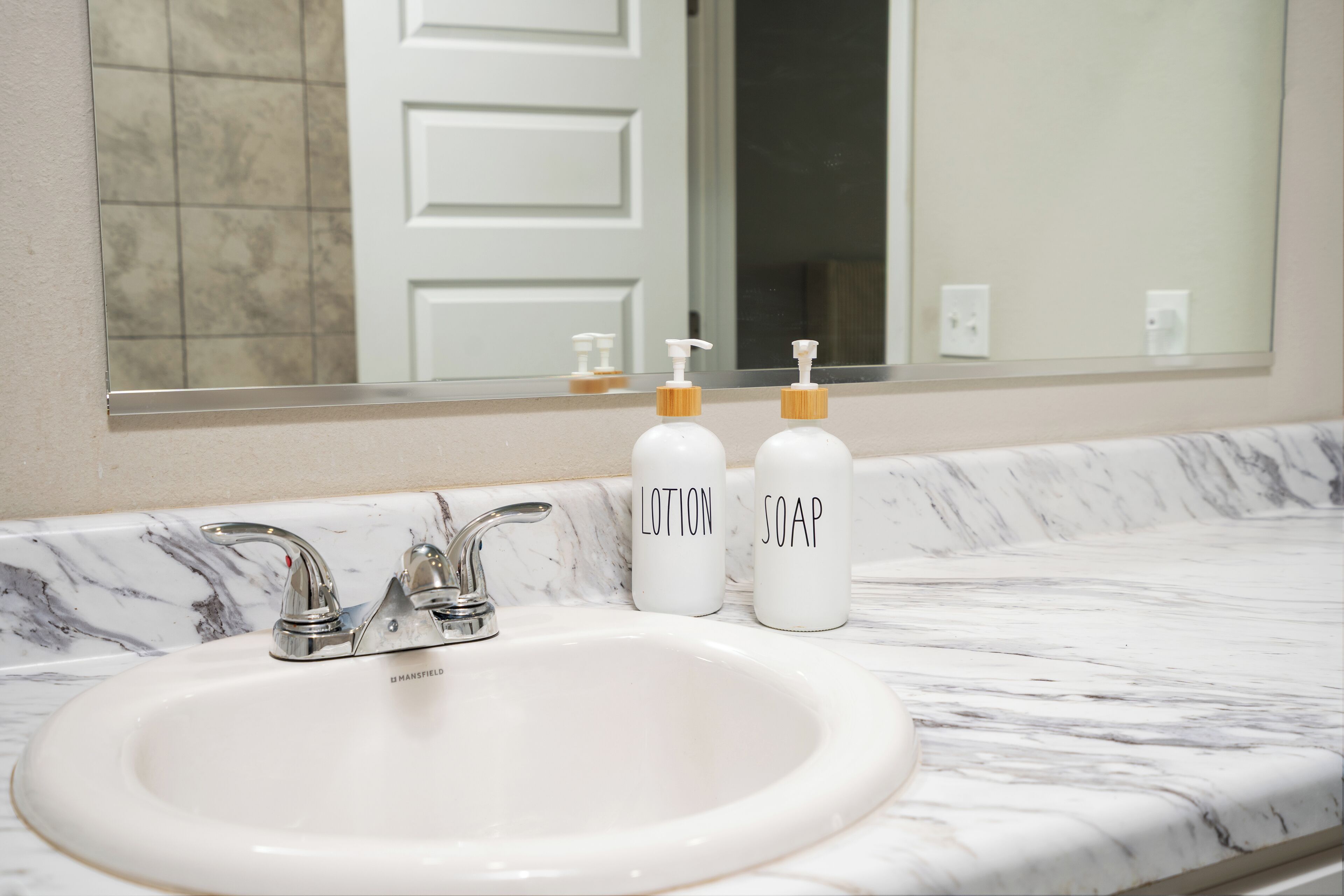 A bathroom with a white sink, two soap dispensers, and a mirror above the sink.