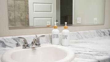 A bathroom with a white sink, two soap dispensers, and a mirror above the sink.
