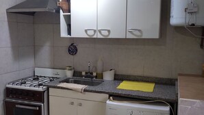 A compact kitchen with a gas stove, oven, washing machine, and a water heater. - The House of Napoli (Trelew)