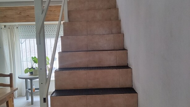 A staircase with a handrail, leading to a landing. - The House of Napoli (Trelew)