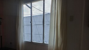 A room with a large window, a tiled floor, and a visible ceiling. - The House of Napoli (Trelew)