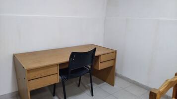 Ein Eckzimmer mit einem Holztisch, einem schwarzen Stuhl und einem weiteren Holzstuhl.