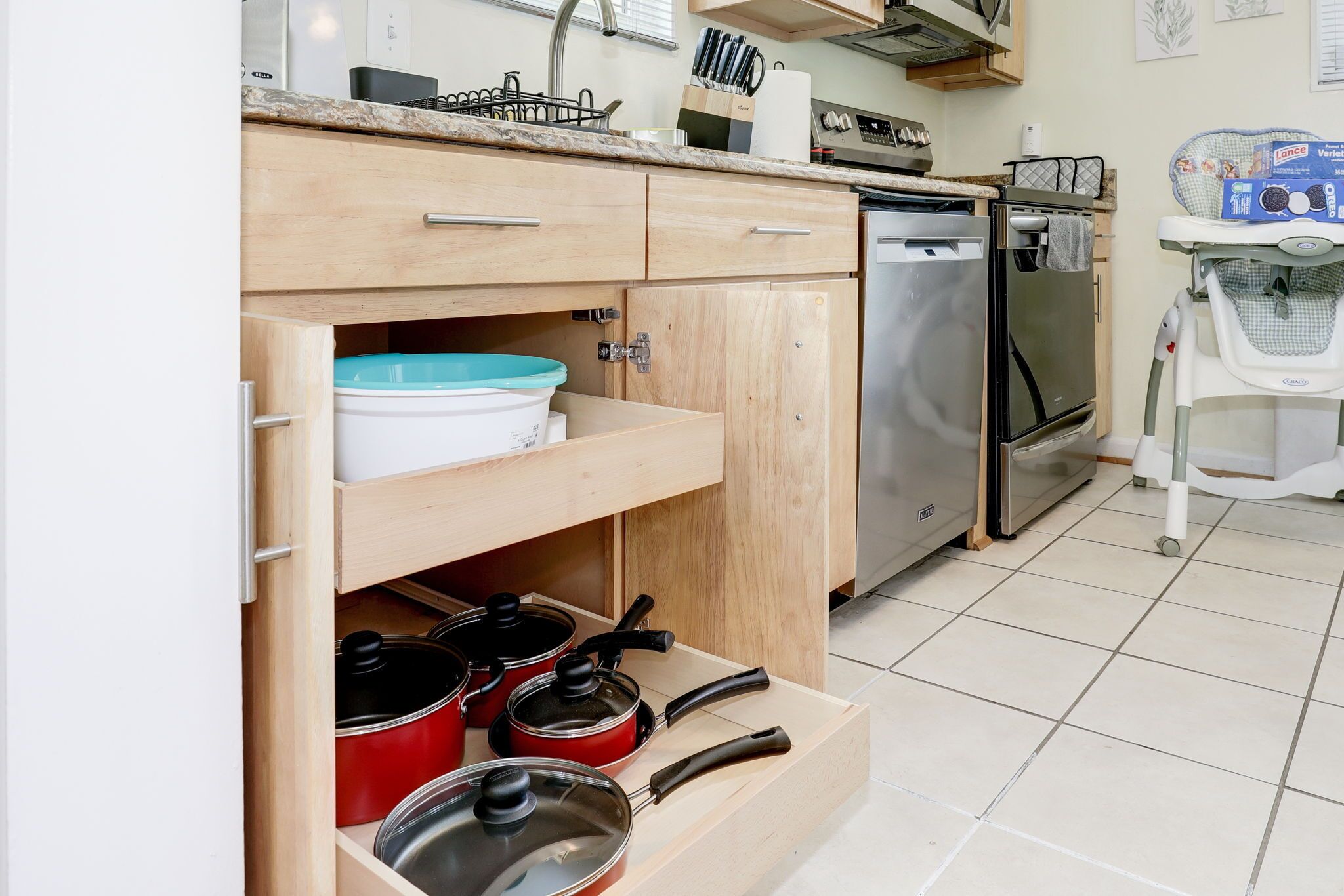Una cucina con mobili in legno, una lavastoviglie e un piano di lavoro con diversi oggetti da cucina.