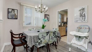 A dining area with a table set for six, surrounded by chairs, a chandelier, and artwork on the walls. - Modern living for visit DC/UMD, 2 bedrooms, 4 beds with central AC/heating (Hyattsville)