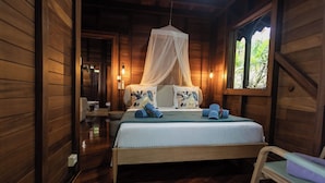 A wooden cabin bedroom with a bed, a canopy, and a window with a view of greenery. - New! Luxurious villa with pool and exceptional view of the Caribbean (Deshaies)