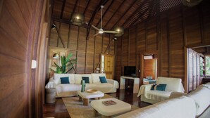 A spacious living room with a high ceiling, wooden beams, a sofa set, a coffee table, and a television. - New! Luxurious villa with pool and exceptional view of the Caribbean (Deshaies)