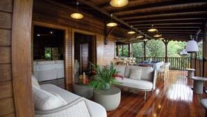 A wooden deck with a sofa, chairs, and a table set for dining. - New! Luxurious villa with pool and exceptional view of the Caribbean (Deshaies)