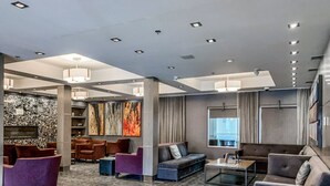 Un hall d’entrée spacieux, doté d’un mobilier moderne, d’un mur décoratif en pierre et d’un grand tableau abstrait.