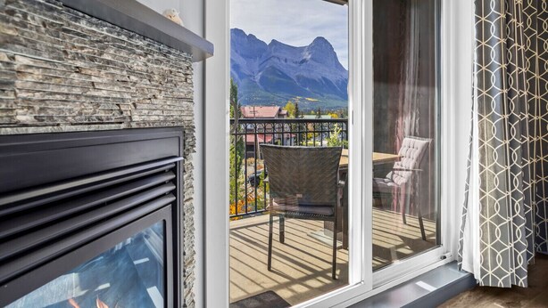Un balcon doté d’une cheminée en pierre, d’un fauteuil en osier et offrant une vue sur les montagnes.