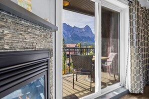 Un balcón con chimenea de piedra, una silla de mimbre y vistas a montañas.