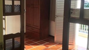 Una habitación con un armario de madera, un ventilador de techo y suelo de baldosas.