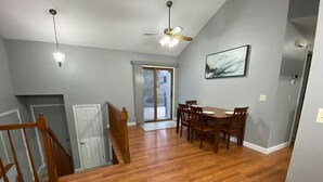 A dining area with a wooden table and chairs, a ceiling fan, and a view through a glass door to an outdoor deck. - Millard West Omaha 4 bed, 3 bath (Omaha)