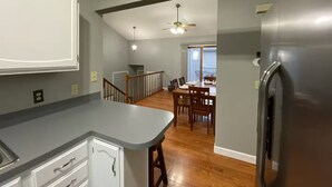 A kitchen with a built-in island, a dining area with a table and chairs, and a refrigerator. - Millard West Omaha 4 bed, 3 bath (Omaha)