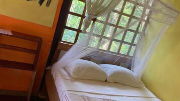 A bed with a canopy, a wall with 'PURA VIDA' written on it, and a window with curtains.
