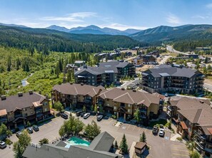 A resort with multiple buildings, a parking lot, and a mountainous backdrop.