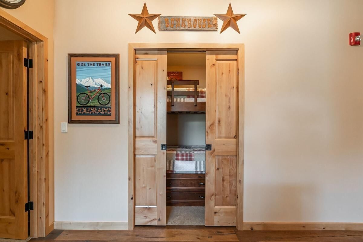 A wooden door with a sign above it, a framed picture on the wall, and a staircase leading to a loft area.