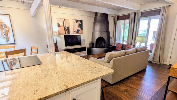 Una cocina moderna con encimeras de granito, horno empotrado y televisor.