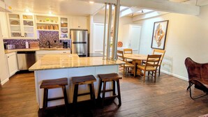 Una cocina amplia con una isla central, taburetes de madera y un comedor con mesa y sillas de madera.