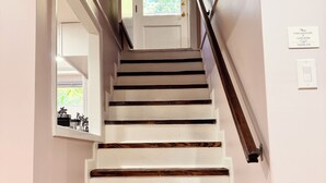 A staircase with white painted steps and dark wooden risers, leading to a door with a window above it.