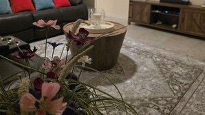 A living room with a sofa, a coffee table with flowers, a TV, and a wooden cabinet.