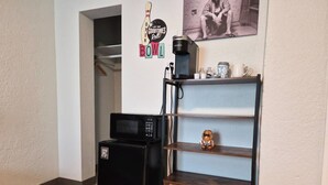 Uma cozinha compacta com micro-ondas, cafeteira e uma prateleira com uma estatueta.