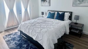 A bedroom with a bed, two bedside tables, a nightstand, a window with curtains, and two wall-mounted artworks. - Play, work, relax, repeat: a sleek 3Bd/3.5Ba retreat near Houston’s top hubs.” (Houston)