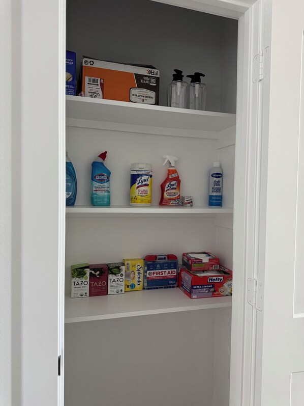 Estante con varios productos de limpieza, incluyendo Lysol, Clorox y un botiquín de primeros auxilios.