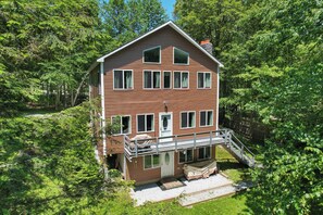 The lodge follows the hillside, with a deck above a ground-level patio. The entire building is pictured; this listing is for the upper unit.