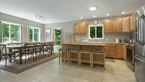 A modern kitchen with a central island, wooden cabinets, and a stainless steel refrigerator.