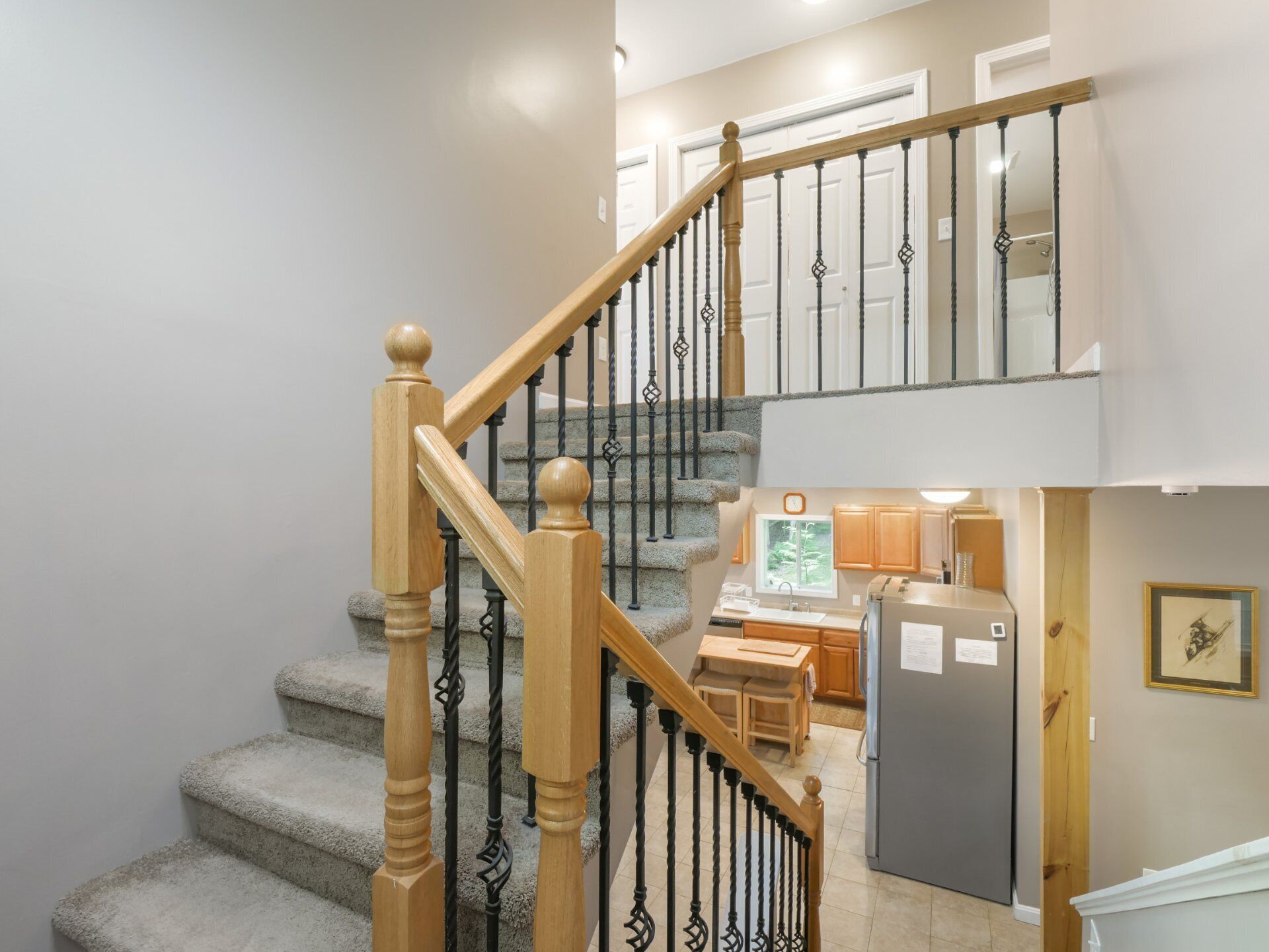 Un escalier avec des balustres en bois et une main courante en pierre menant à un palier situé au deuxième étage.
