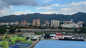 A cityscape with a mountain range in the background, a parking lot, and several buildings.