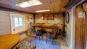 Un'area pranzo rustica con sedie di legno, un tavolo rotondo e una parete in pietra.