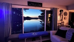 Une pièce dotée d’une grande fenêtre donnant sur un lac, d’un banc et d’un panneau indiquant : « Faites une pause au bord du lac ».