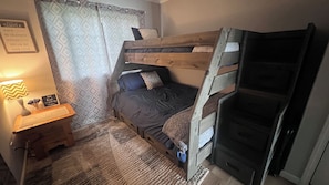 A bunk bed room with a small bedside table, a lamp, and motivational posters.