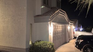Un immeuble résidentiel doté d’un garage, d’une allée et d’un véhicule stationné.